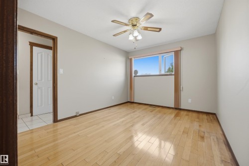 Light wood-finish flooring, a ceiling fan with integrated lighting, and a window with a light-colored frame - 14008 94 Street Nw, Edmonton, AB 