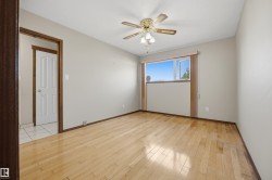 Light wood-finish flooring, a ceiling fan with integrated lighting, and a window with a light-colored frame - 