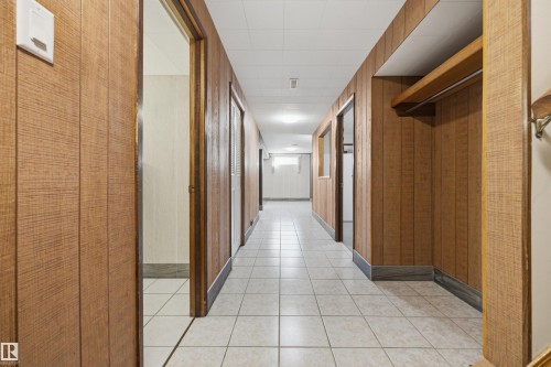 Hallway with wood-finish paneling, white square tile flooring, drop ceiling, and recessed lighting - 14008 94 Street Nw, Edmonton, AB 