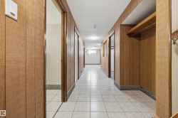 Hallway with wood-finish paneling, white square tile flooring, drop ceiling, and recessed lighting - 