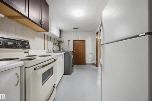 Functional kitchen space featuring white appliances, a top-mount sink, and dark wood-finish cabinetry - 14008 94 Street Nw, Edmonton, AB 