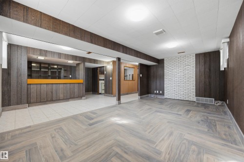 Herringbone wood-finish flooring, white brick accent wall, wood paneling, built-in bar with shelving, and recessed lighting - 14008 94 Street Nw, Edmonton, AB 