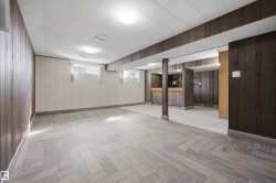 Herringbone wood-finish flooring, recessed lighting, wood paneling, and a built-in bar - 