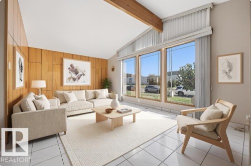Vaulted ceiling with exposed wood beam, full-height paneled wall, large picture windows, and light-toned tile flooring - 14008 94 Street Nw, Edmonton, AB 
