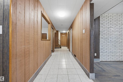 Hallway with wood-finish paneling, white ceramic tile flooring, and a window opening - 14008 94 Street Nw, Edmonton, AB 