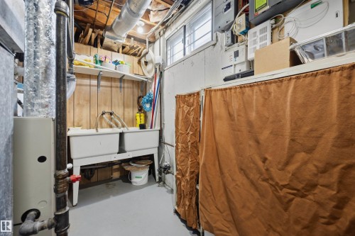 Utility area with a double basin sink, exposed ceiling joists, and a hot water heater - 14008 94 Street Nw, Edmonton, AB 