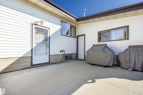 Expansive concrete patio with white siding and brown trim - 14008 94 Street Nw, Edmonton, AB 
