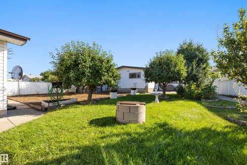 Expansive lawn area, mature trees, white privacy fencing, concrete patio, and garden beds - 14008 94 Street Nw, Edmonton, AB 