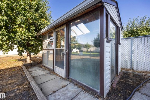 Greenhouse structure with multiple glass panels, white siding, and a gabled roof - 14008 94 Street Nw, Edmonton, AB 