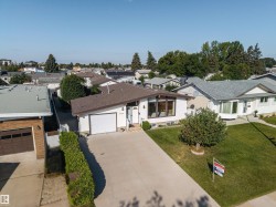 White exterior siding with a brown shingle roof, attached garage, and a concrete driveway - 