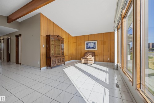 White tile flooring, wood panel accent wall, exposed wood beam, and large windows - 14008 94 Street Nw, Edmonton, AB 