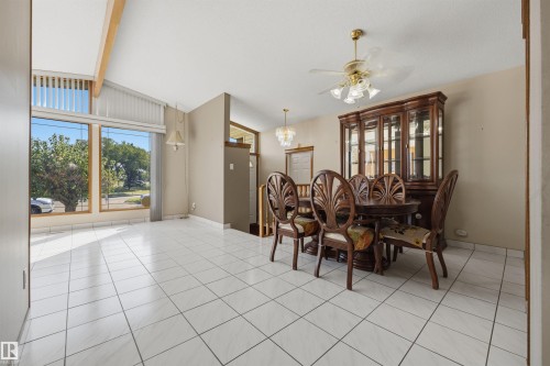 Vaulted ceiling with exposed wood beams, large picture windows, white tile flooring, and a ceiling fan with integrated lighting - 14008 94 Street Nw, Edmonton, AB 