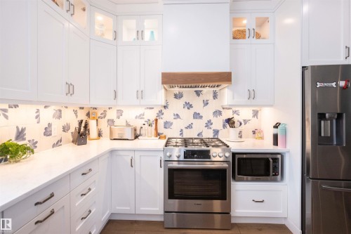 U-shaped kitchen featuring white cabinetry, quartz countertops, and a patterned tile backsplash - 5404 60Th Street, Barrhead, AB - Indoor Photo Showing Kitchen