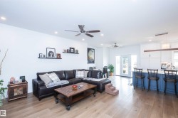 Open-concept living area featuring wood-finish flooring, recessed lighting, and multiple ceiling fans - 