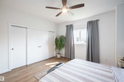 Bedroom featuring wood-finish flooring, a ceiling fan with integrated lighting, and a window with white trim - 