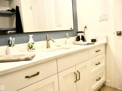 Modern vanity featuring white shaker-style cabinetry, a light-toned countertop, an undermount sink, and a brushed nickel faucet - 
