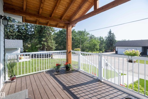 Covered porch featuring wood-finish decking and a natural wood-beamed ceiling - 5404 60Th Street, Barrhead, AB - Outdoor With Deck Patio Veranda With Exterior