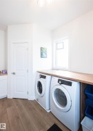 Dedicated laundry area featuring wood-finish flooring, a wood countertop, and white cabinetry - 