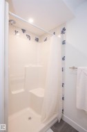 Shower stall with integrated seating and grab bar, complemented by decorative tiled accents and a brushed metal towel bar - 