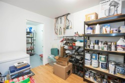 Utility room with wood-finish flooring, white walls, and an open doorway to an additional storage area - 
