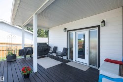 Covered deck with dark wood-finish flooring, white siding, and outdoor wall sconces - 