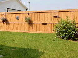 Expansive lawn space featuring a privacy fence, mature shrubbery, and a visible garage exterior - 