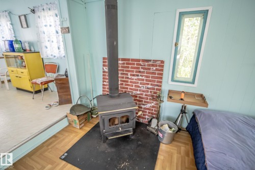 Wood-burning stove with a brick-patterned back panel - 811 59209 Range Rd 95A, Rural St. Paul County, AB - Indoor Photo Showing Bedroom