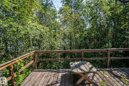 Wood deck with a natural wood railing, surrounded by mature trees - 811 59209 Range Rd 95A, Rural St. Paul County, AB - Outdoor With Deck Patio Veranda