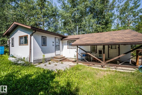 Single-story residence featuring white exterior siding, a brown shingle roof, and a covered porch with wood railing - 811 59209 Range Rd 95A, Rural St. Paul County, AB - Outdoor