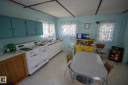 Kitchen featuring light blue walls, built-in cabinetry with light blue upper doors, white built-in appliances, and light-colored flooring - 811 59209 Range Rd 95A, Rural St. Paul County, AB - Indoor Photo Showing Other Room