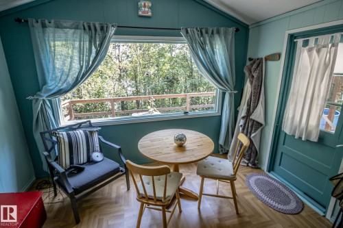 Room with wood-finish flooring and a central window overlooking a wooden deck railing and trees - 811 59209 Range Rd 95A, Rural St. Paul County, AB - Indoor Photo Showing Dining Room