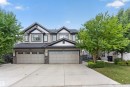 Contemporary exterior featuring gabled rooflines, stone and siding accents, dual garage doors with transom windows, and a paved driveway - 5130 Godson Close Nw, Edmonton, AB 