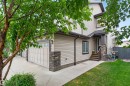 Two-story exterior with light-toned siding, stone accents, concrete driveway, and a covered entry - 5130 Godson Close Nw, Edmonton, AB 