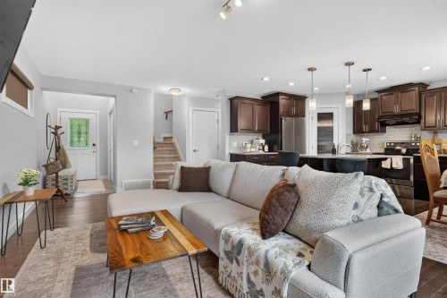 Open-concept living space featuring wood-finish flooring, recessed lighting, and a kitchen with dark cabinetry and pendant lights - 5130 Godson Close Nw, Edmonton, AB 