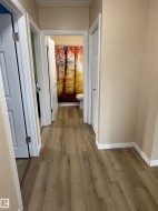 Hallway featuring wood-finish flooring and light-toned walls - 
