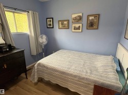 Interior room featuring a window with privacy curtains, light blue wall paint, and wood-finish flooring - 