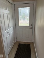 Entryway featuring a white door with decorative glass inserts, light wood-finish flooring, and a bifold closet - 