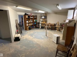 Spacious lower level with concrete flooring, exposed structural beams, and built-in fluorescent lighting - 