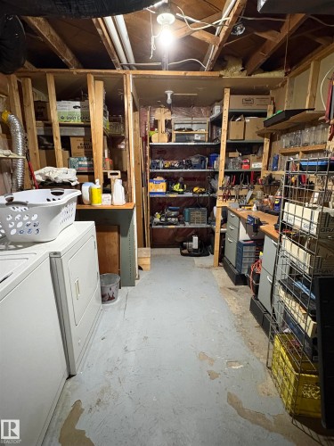 Unfinished basement featuring exposed ceiling joists, concrete flooring, and built-in shelving - 5308 50 St, Ryley, AB 