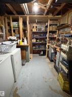 Unfinished basement featuring exposed ceiling joists, concrete flooring, and built-in shelving - 