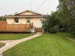 Rear exterior featuring light-toned siding and a brown shingle roof - 