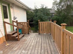 Exterior wood deck featuring a wooden railing, steps, and privacy gate - 