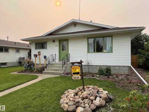 Single-story residence featuring white siding, a green entry door, and a concrete pathway - 5308 50 St, Ryley, AB 