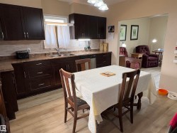 Kitchen featuring dark wood-finish cabinetry, light wood-finish flooring, a double basin sink, and a light-toned tile backsplash - 