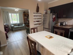 Kitchen area featuring dark wood-finish cabinetry, a stainless steel refrigerator, and a stone-look countertop - 