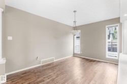 Wood-finish flooring, neutral wall tones, white trim, and a built-in chandelier - 