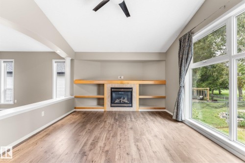 Wood-finish flooring, built-in fireplace with tile surround, integrated shelving, and large picture windows - 2060 Brennan Crescent Nw, Edmonton, AB 