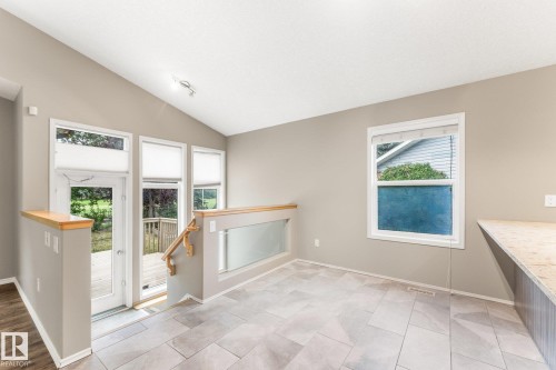 Vaulted ceiling, patio door, deck access, tile flooring, and a glass-paneled railing - 2060 Brennan Crescent Nw, Edmonton, AB 