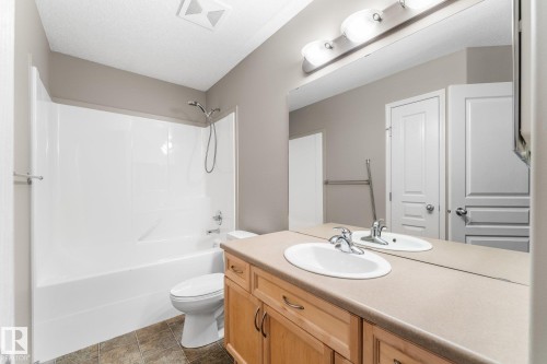 Bathroom featuring a single vanity with a laminate countertop, light wood-finish cabinetry, an undermount sink, and a combination shower and tub - 2060 Brennan Crescent Nw, Edmonton, AB 