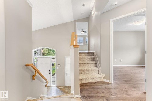 Vaulted entryway with an arched transom window, wood-finish flooring, and carpeted stairs with wood handrails - 2060 Brennan Crescent Nw, Edmonton, AB 